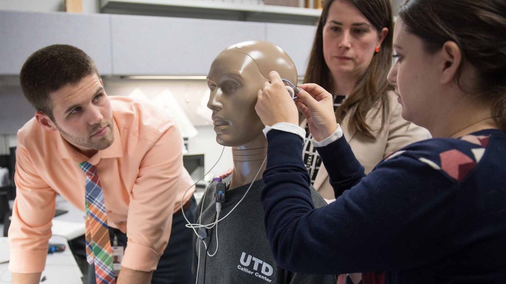 students adjusting an ear piece on a mannequin